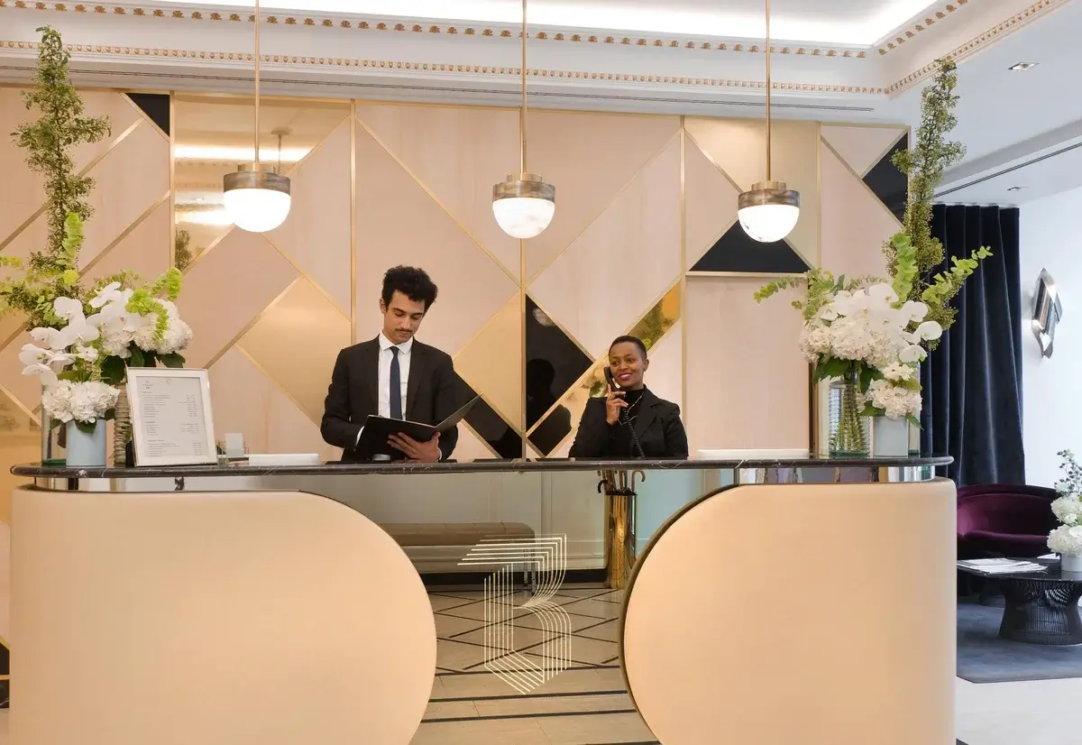 The hotel reception desk features two staff members engaging in communication and sharing objectives showcasing a revenue management trend.